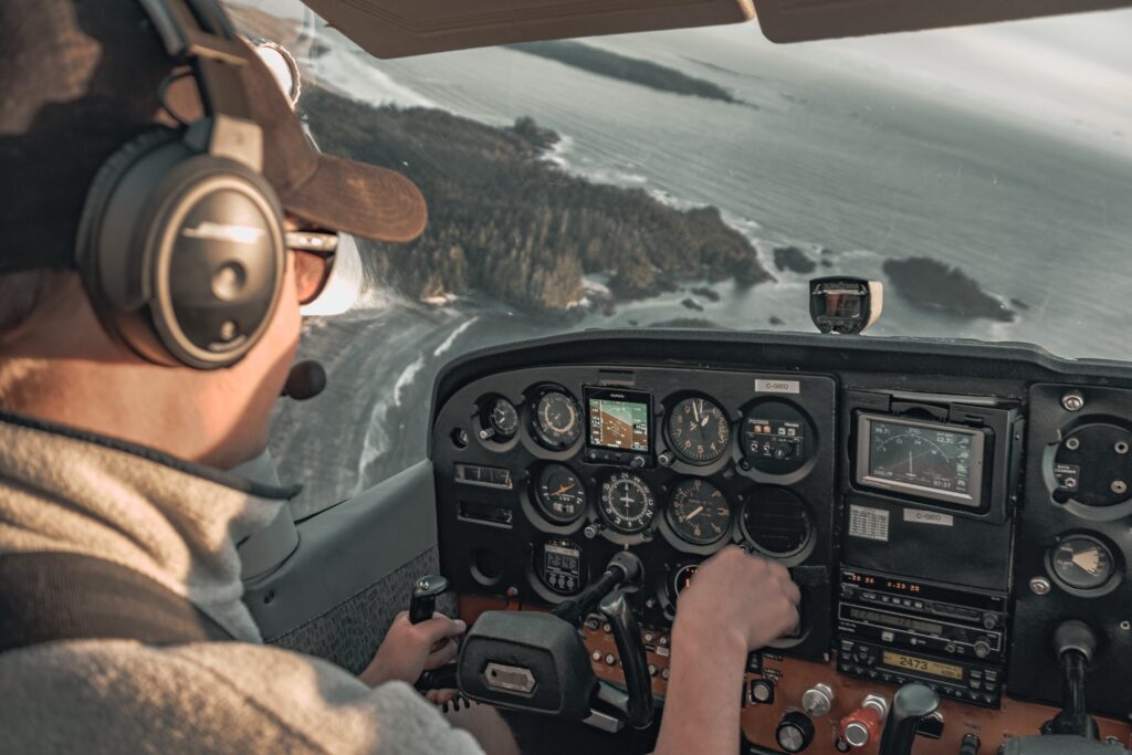 GPT Pilot operating the controls in the cockpit of a small aircraft, with a view over coastal terrain visible through the windshield.